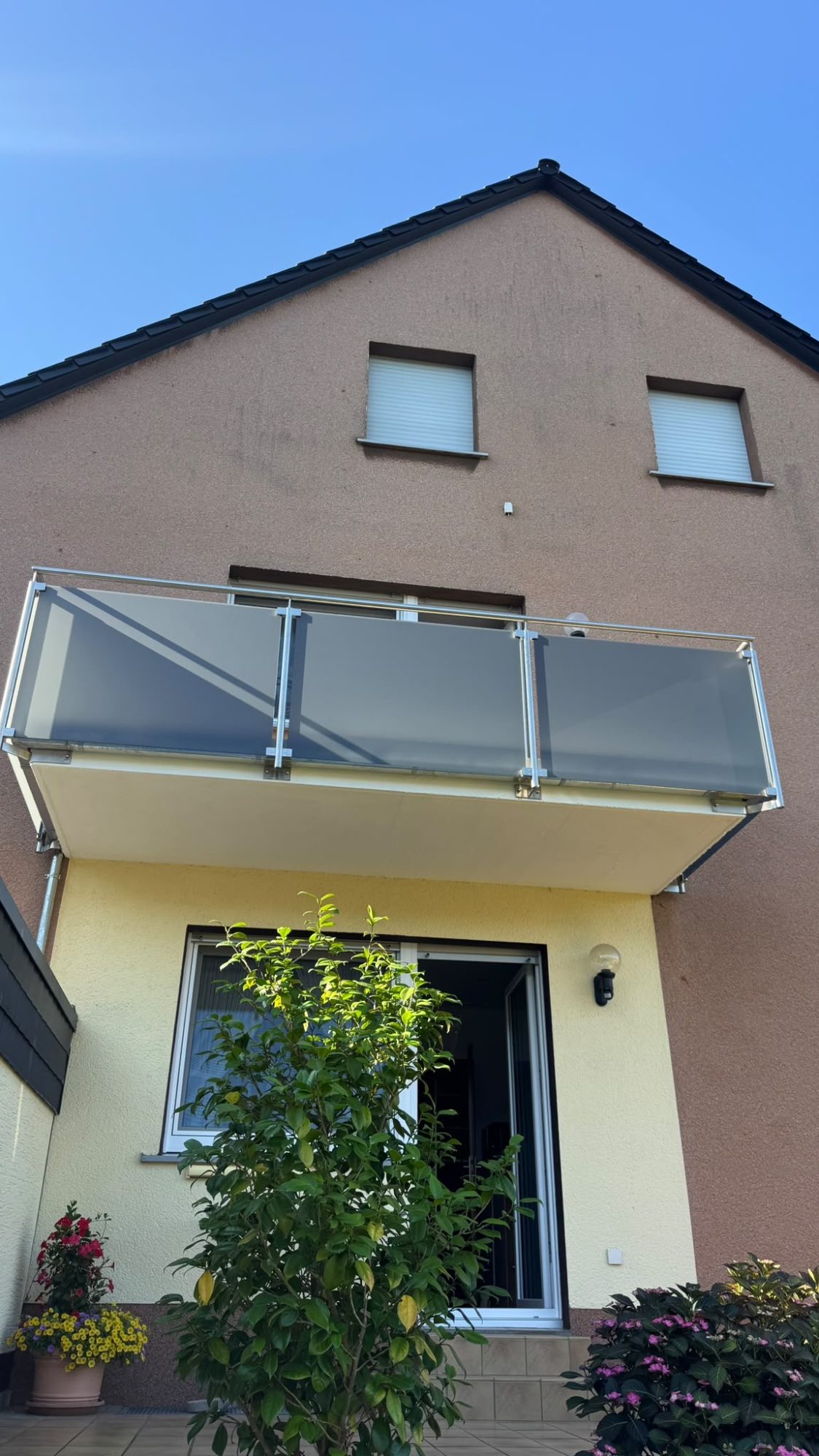 Edelstahlgeländer am Balkon mit graues Glas, seitliche Befestigung