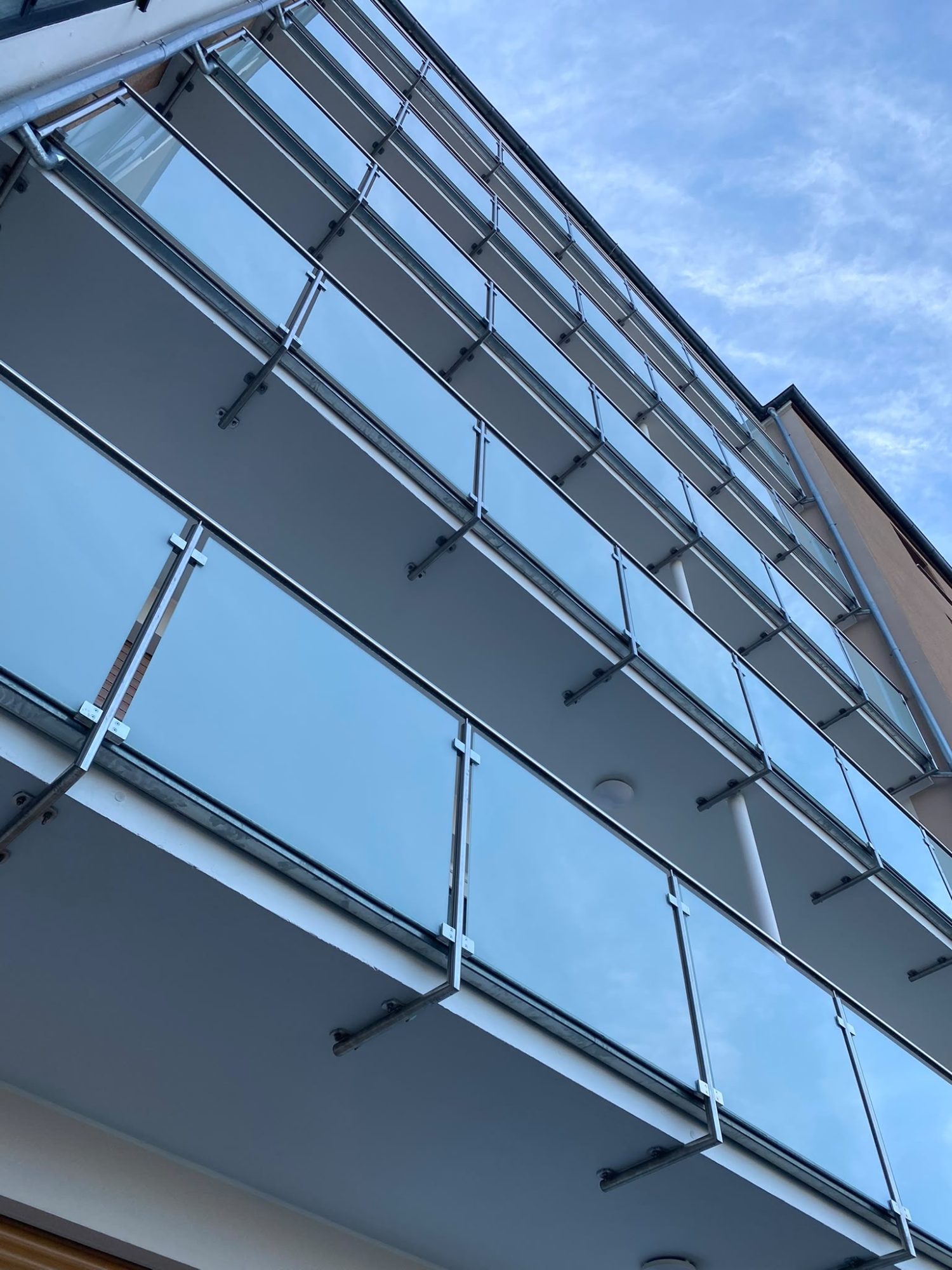 Edelstahlgeländer an Balkonen mit mattem Glas, Befestigung von unten